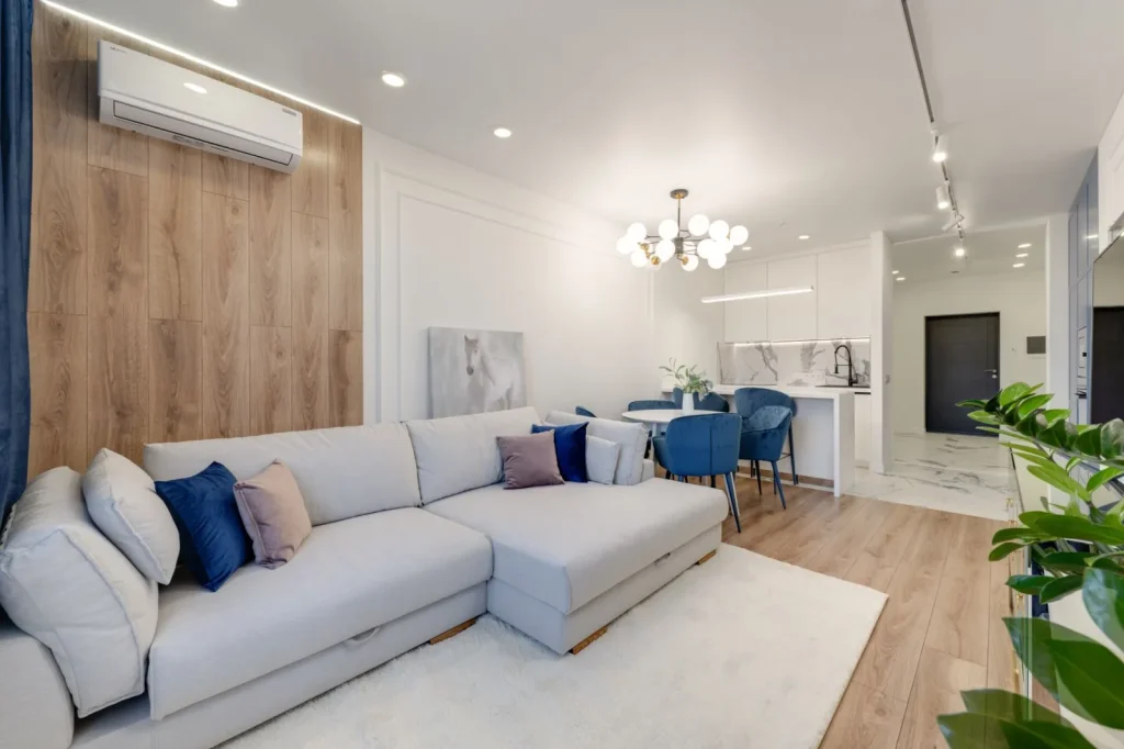 A room air purifier running on a hardwood floor next to a sofa in a bright living room