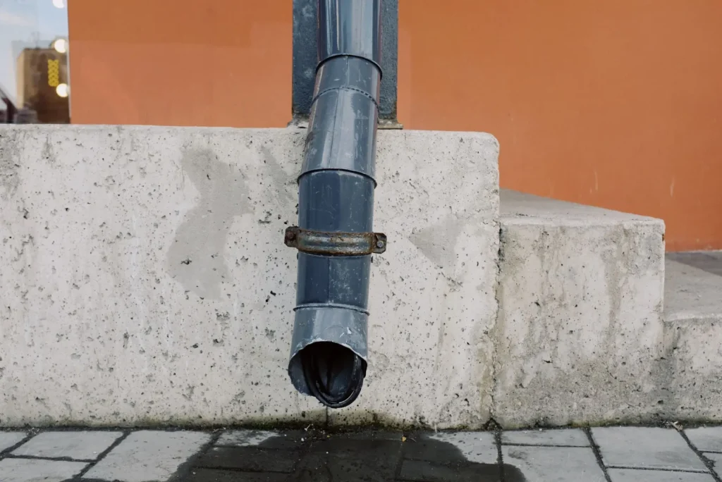 A downspout extension carrying roof water several feet away from a house foundation