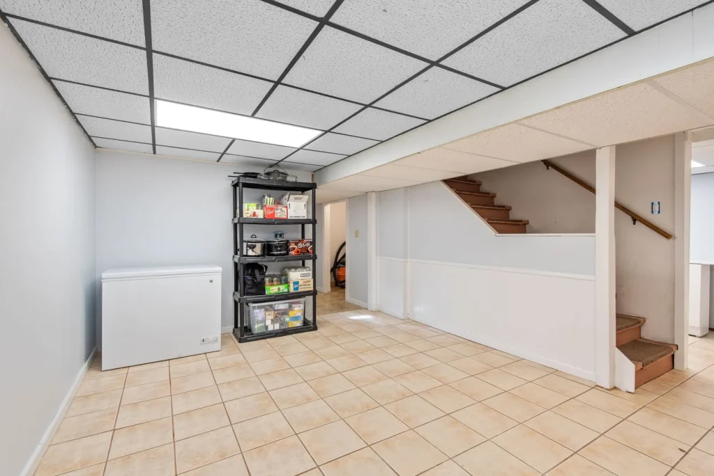 A white portable dehumidifier running in the corner of a finished basement