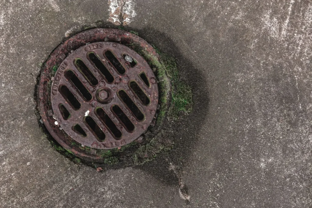 A portable dehumidifier with a drain hose running to a basement floor drain