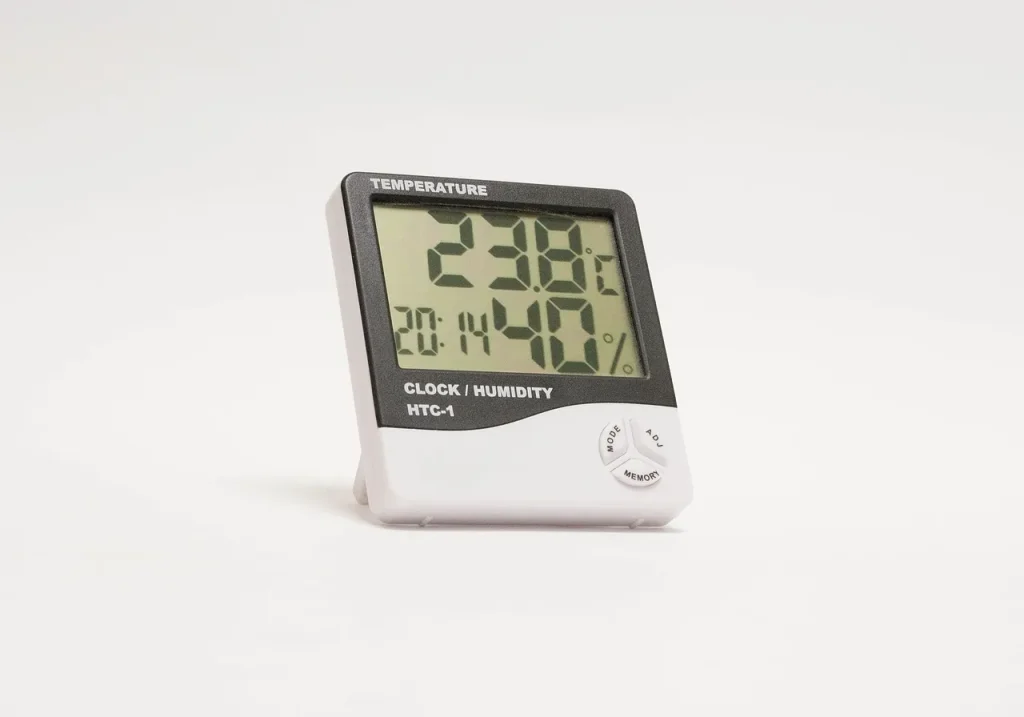 A hygrometer sitting on a basement floor showing the room humidity and temperature reading used to diagnose a dry dehumidifier