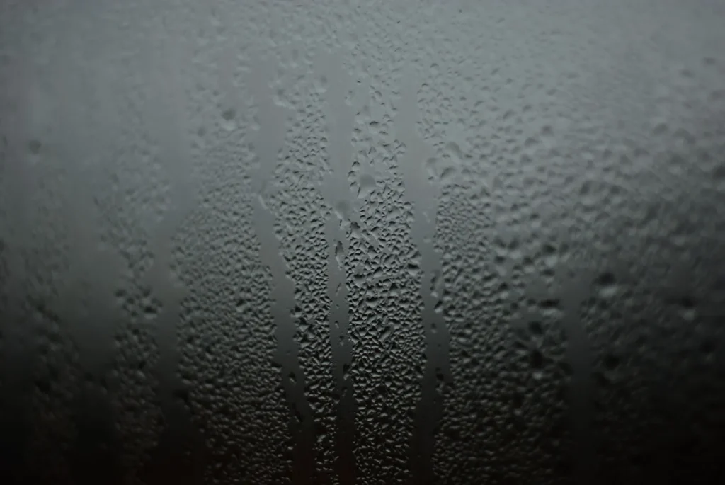 Water condensation beading on the inside of a cold window pane on a winter morning