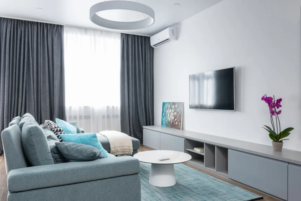 A portable HEPA air purifier running in a home living room next to a sofa