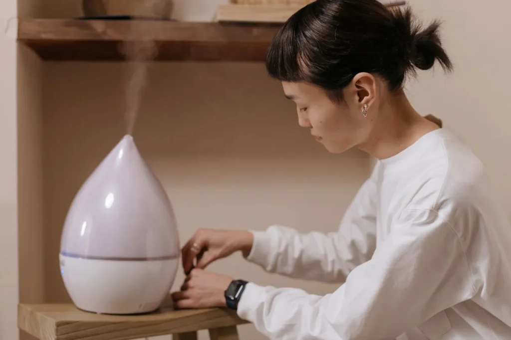 An ultrasonic humidifier releasing a visible plume of cool mist on a bedside table