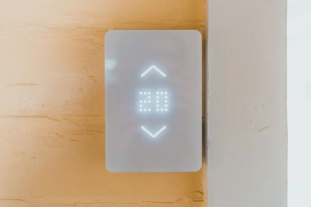 A digital HRV wall control mounted on a home wall showing fan speed and humidity settings