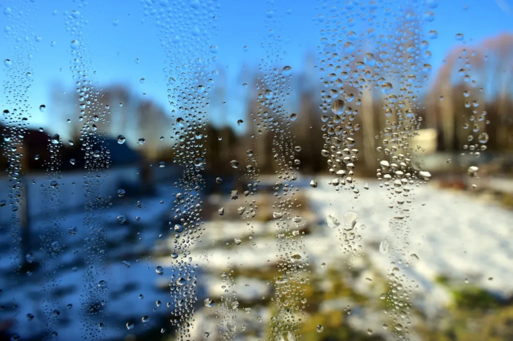 Condensation forming on a home window during cold weather, a sign of high indoor humidity