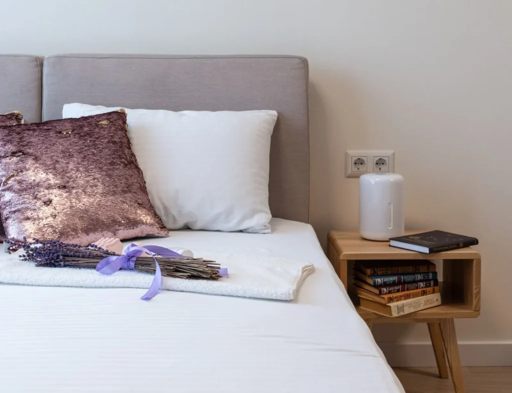A cool mist humidifier running on a bedroom nightstand with visible vapor