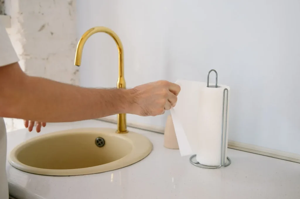 Hands cleaning a humidifier water tank at a kitchen sink