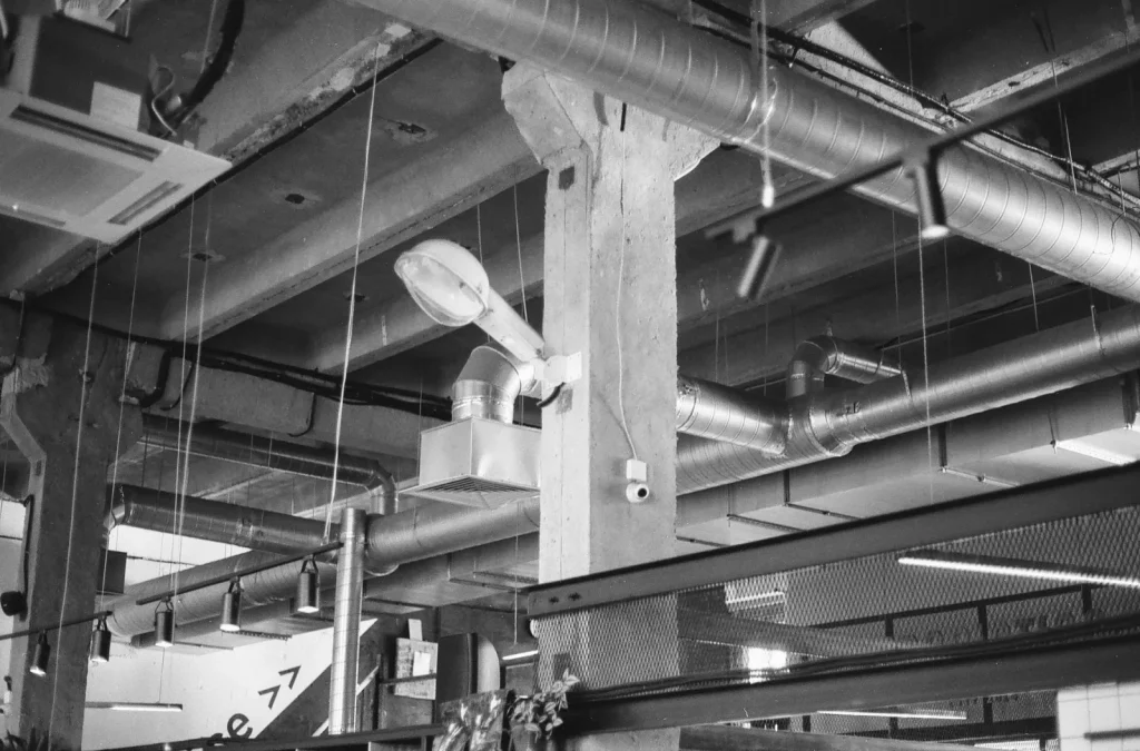 A wall-mounted heat recovery ventilator with insulated ducts running to it in a basement