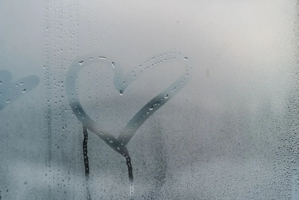 Water condensation beading and running down the inside of a cold window pane