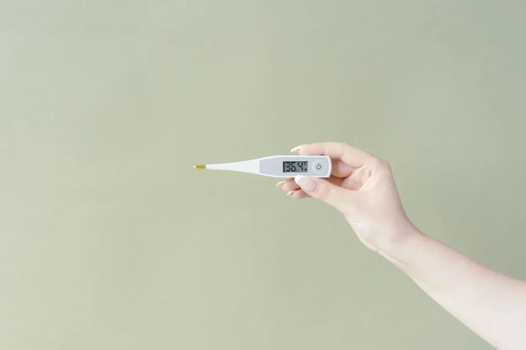 A hand holding a small digital hygrometer displaying indoor relative humidity in a home room.