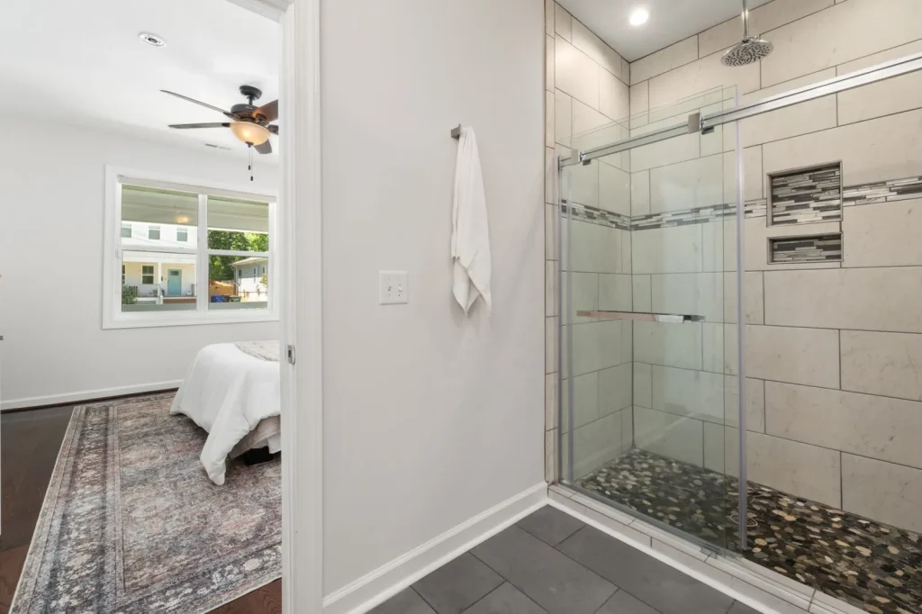 A white ceiling-mounted bathroom exhaust fan installed near a shower