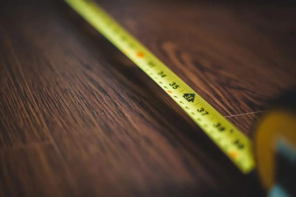 Measuring a bathroom floor with a tape measure to calculate square footage