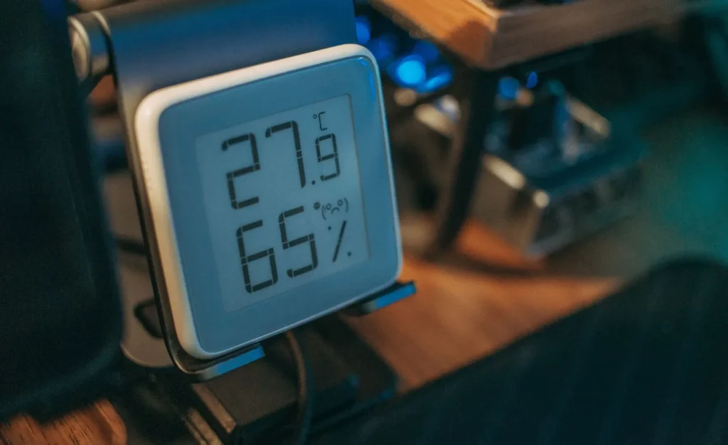 A digital hygrometer displaying indoor relative humidity next to a humidifier
