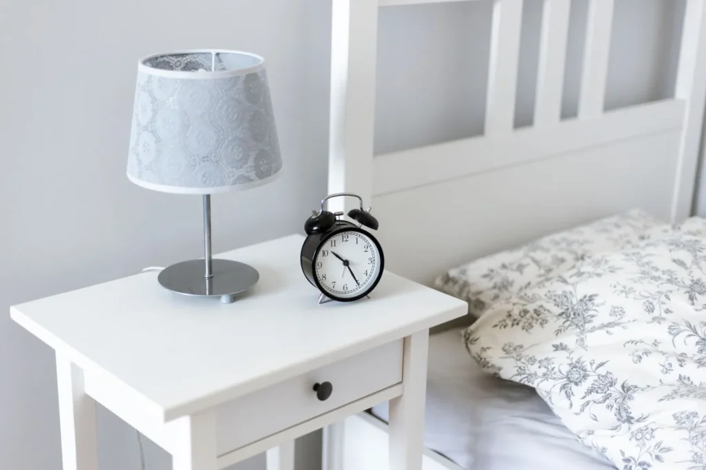 A cool mist humidifier running on a bedroom nightstand next to a small digital hygrometer