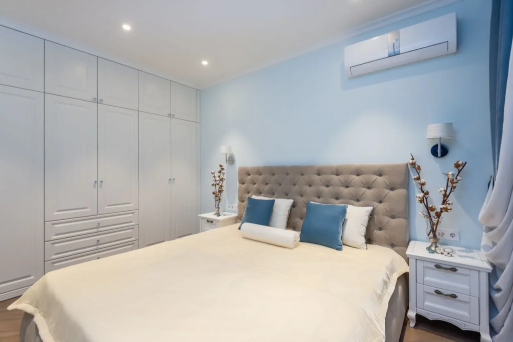 A cool mist humidifier running on a bedroom nightstand a few feet from the bed