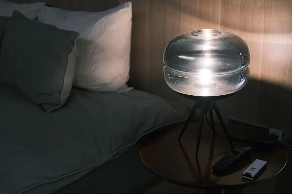 A cool-mist humidifier releasing vapor next to a bed in a calm bedroom