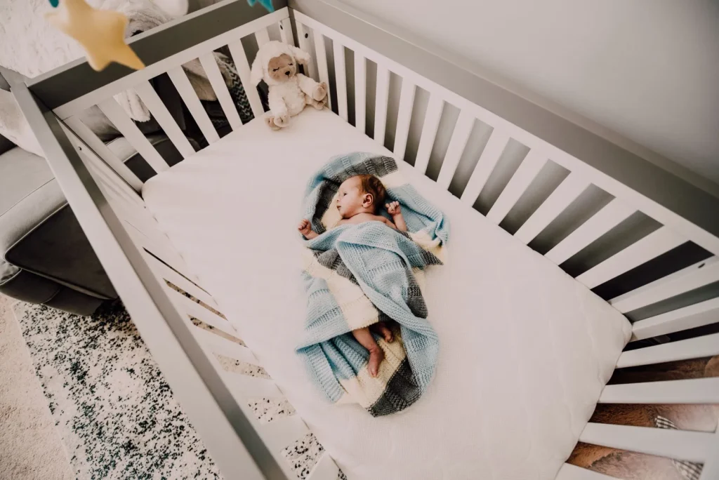 A cool-mist humidifier placed on a dresser several feet away from a baby's crib in a bright nursery