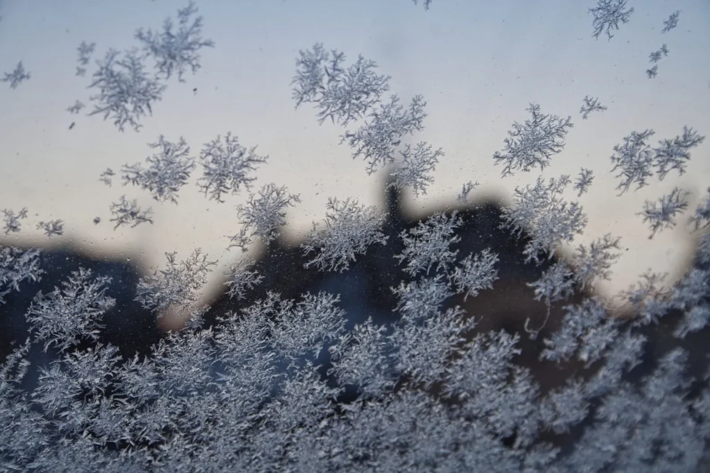 Condensation and frost forming on the inside corner of a cold winter window