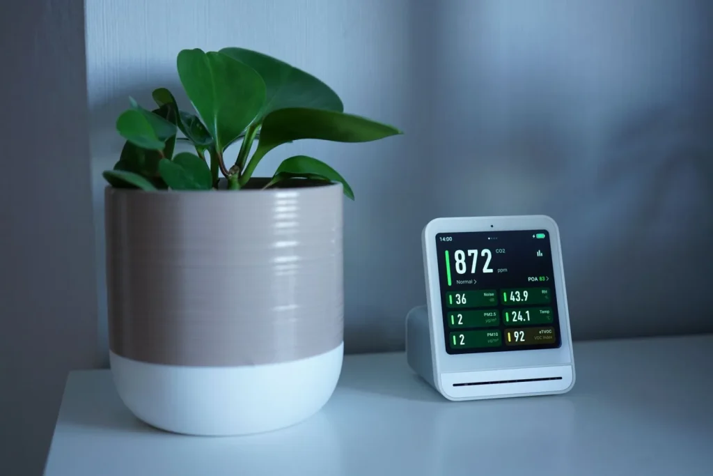 A small home air quality monitor sitting on a kitchen counter displaying PM2.5 and humidity readings