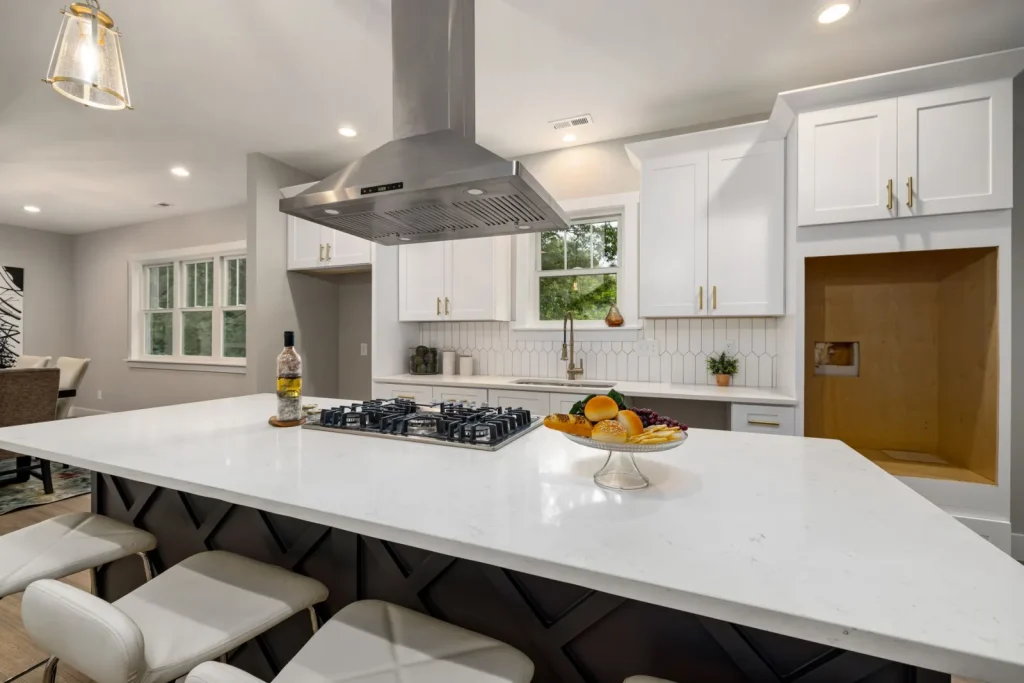 A kitchen range hood running over a gas stove while food sears in a pan, capturing cooking smoke