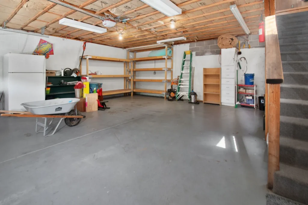 A portable dehumidifier running in a finished basement with a hose draining to a floor drain