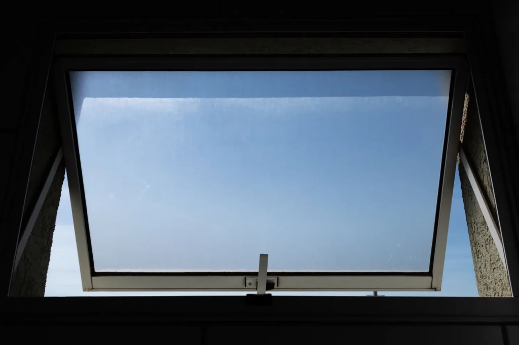 Sunlight streaming through an open window highlighting airborne pollen dust in a living room