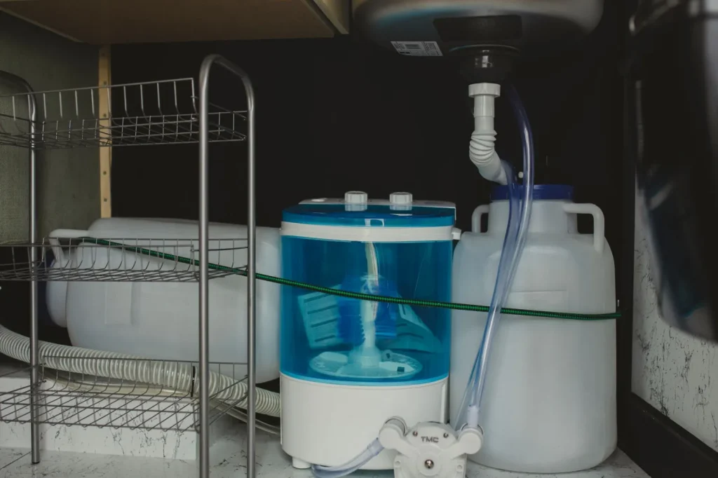 A portable dehumidifier running in a basement with a drain hose routed to a floor drain