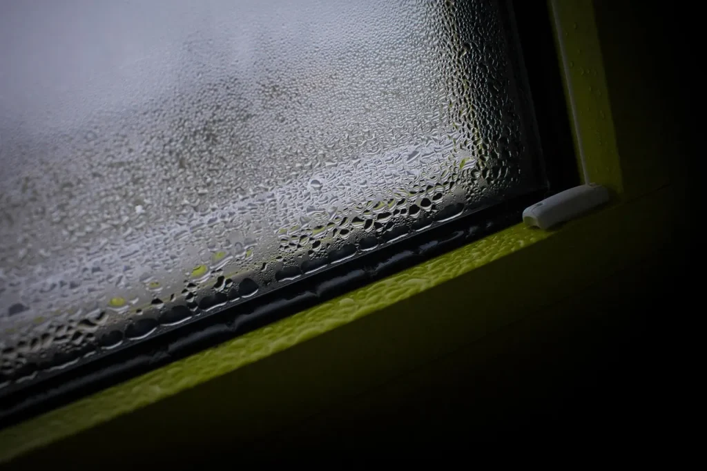 Fogged bedroom window with condensation collecting along the bottom of the glass