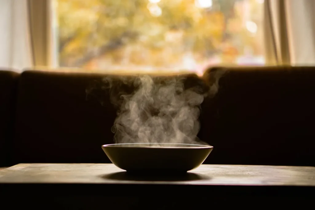A steam humidifier producing warm vapor in a home bedroom