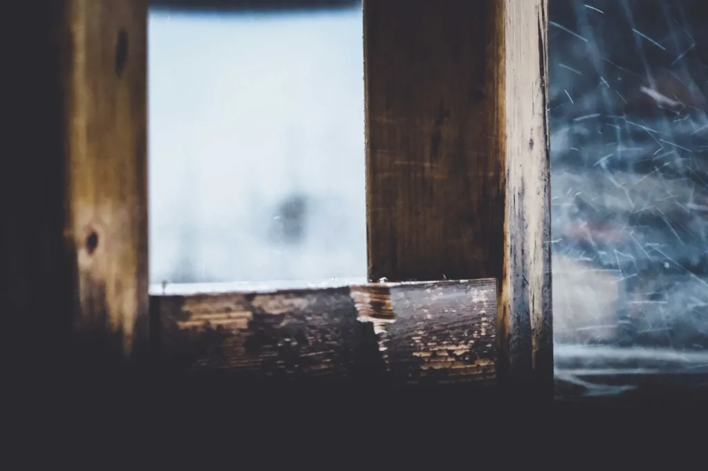 An old double-hung wooden sash window in a period home, the kind of spot where air leaks in older houses