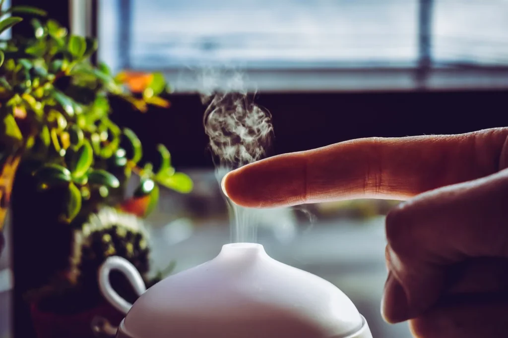 A warm mist humidifier releasing visible vapor on a bedroom nightstand