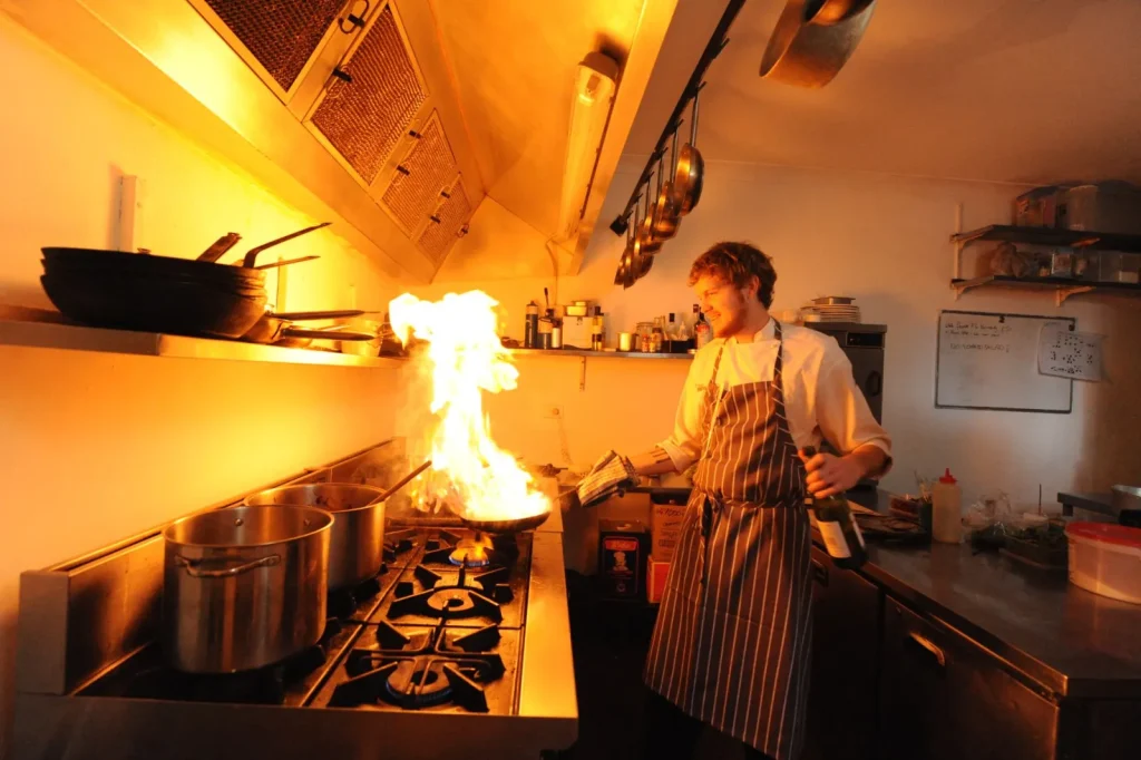 Range hood exhaust fan pulling steam and cooking particles away from a stovetop
