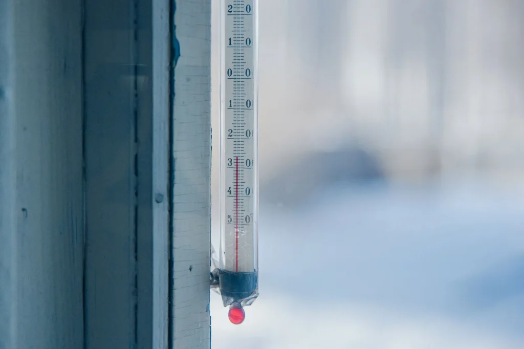 A digital hygrometer showing indoor relative humidity during winter next to a frosted window