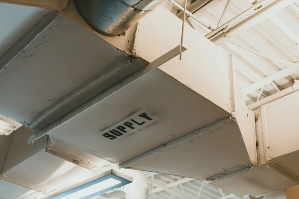 A bypass whole house humidifier mounted on furnace ductwork with its water line and humidistat visible